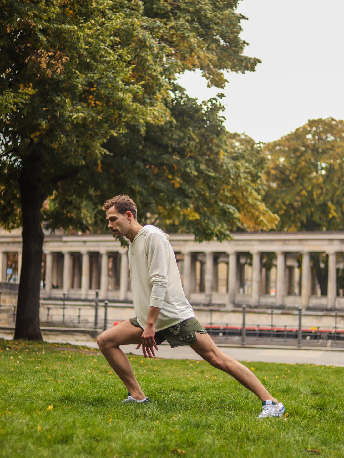 A young man doing lower body stretches in a green patch